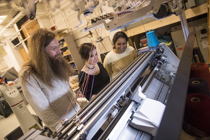 James McCann, Lea Albaugh and Vidya Narayanan watch Shima Seiki’s SWG091N2 15-gauge V-bed knitting machine work on a 3D shape. © Carnegie Mellon University