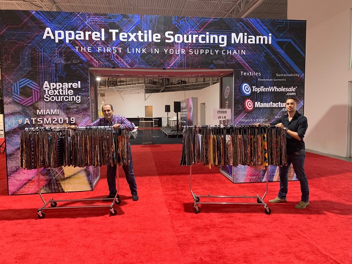 Chase Vance, Director of ATSM, helps exhibitor Sean Zarini, of LA-based Fabric Selection, set up for Apparel Textile Sourcing Miami. © ATSM