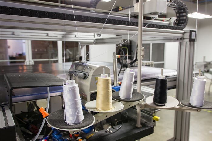 The company’s Sewbots use a combination of patented high-speed computer vision and lightweight robotics to steer fabric to and through the needle. © SoftWear Automation 