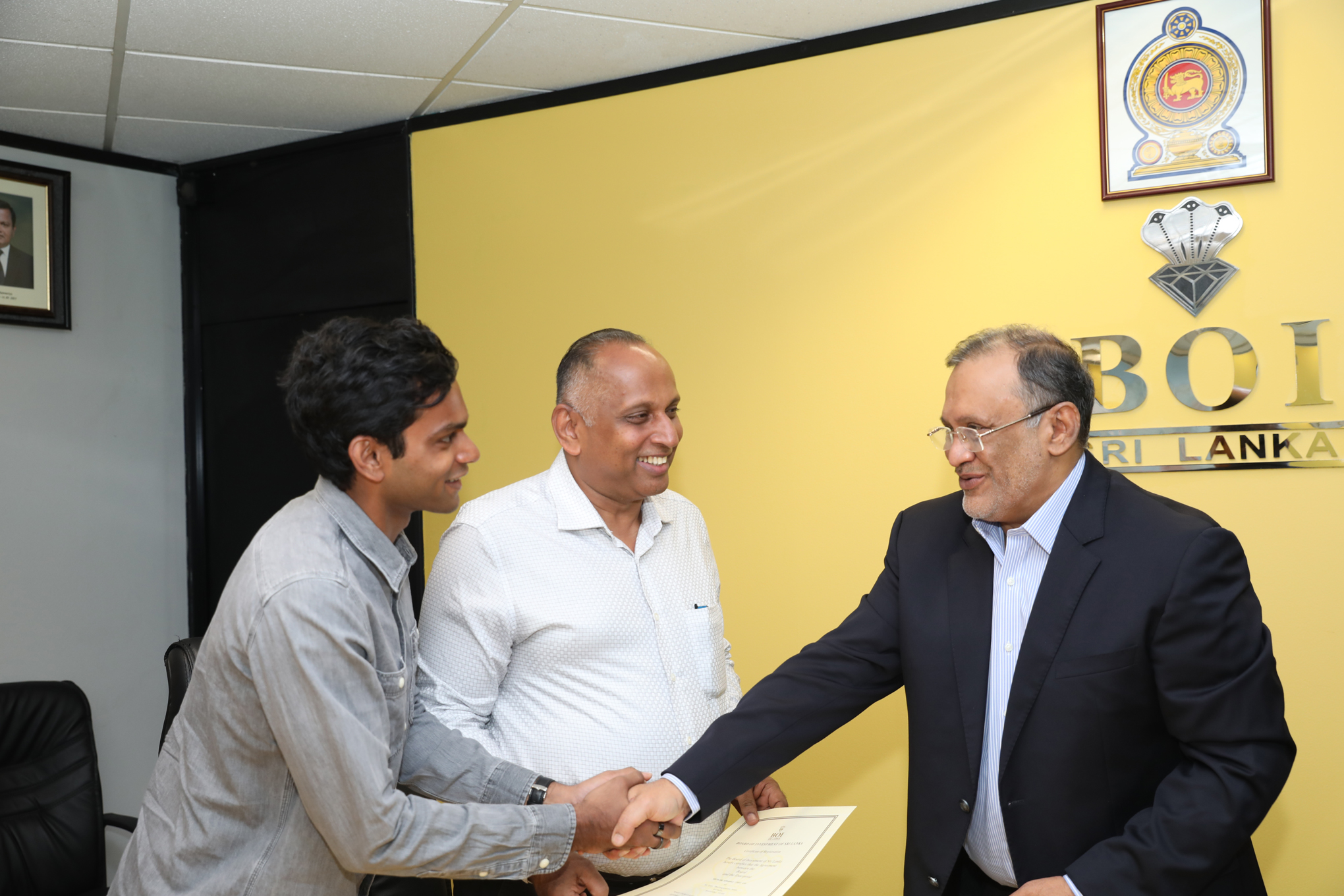 Chairman BOI Susantha Ratnayake formally hands over the Certificate of Registration to Mohamed Onies, Chairman/ Director and Riz Onies, CEO of Knitline. © Board of Investment.