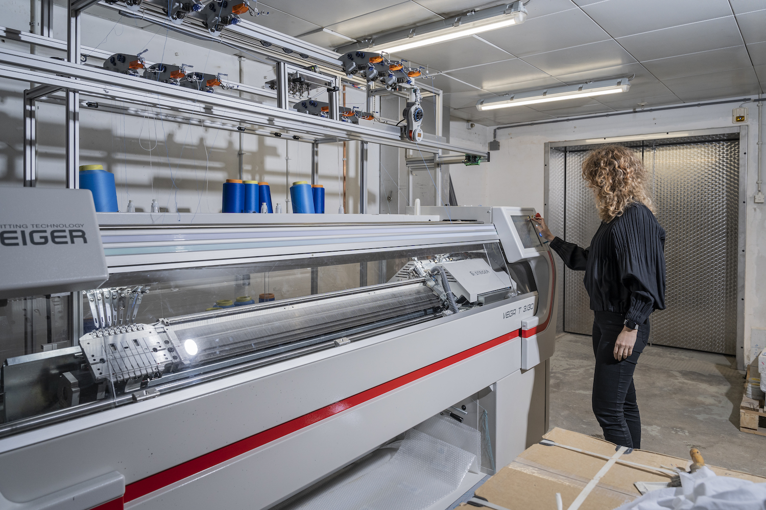 Mariana Popescu knitting in the lab on her Steiger flat knitting machine. © TU Delft | Adam Klugkist
