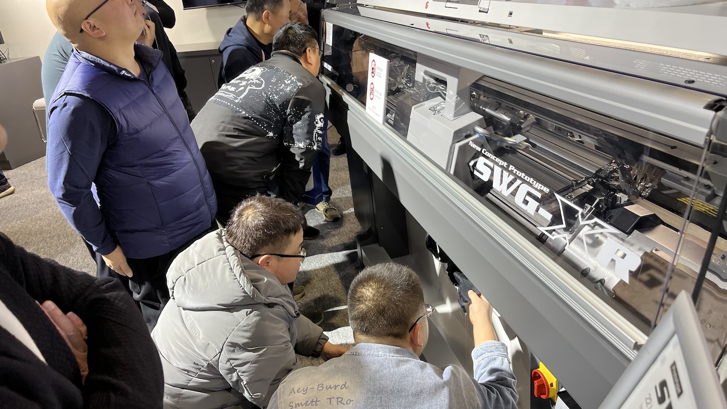 Visitor’s clamber to get a close look at the SWG-XR Prototype WHOLEGARMENT knitting machines. © Shima Seiki