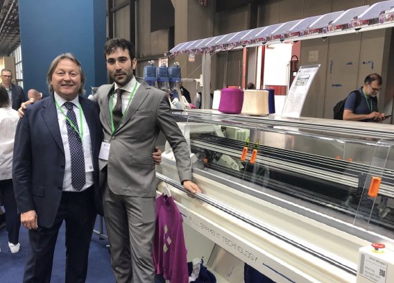 Mandarin Founder and CEO Sante De Pecol (left) with head of marketing Niccolò Franchin, and the company’s 7.2-gauge FG-372 SYF Full Garment knitting machine at ITMA 2023 in Milan. © Knitting Industry